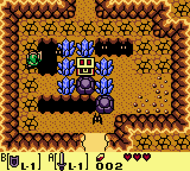Still frame: an orange cave room with dark pits, blue crystals and a yellow block with a face in the middle. Link is on the left edge.